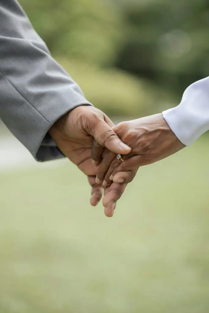 two hands connected. One is wearing a grey suit and one is wearing a white sleeve