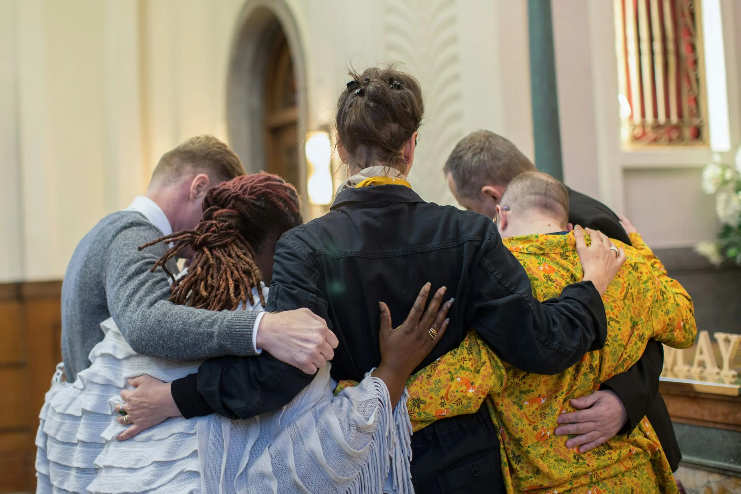 the backs of 5 people embraced inside a church