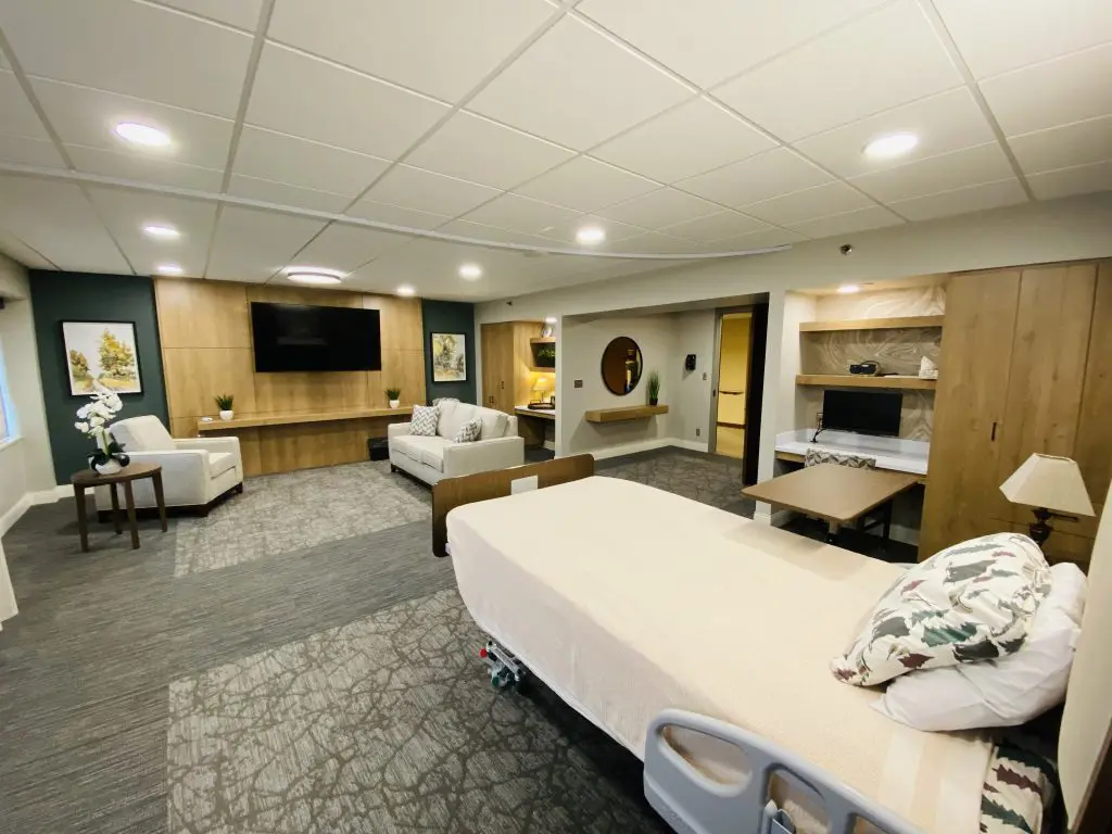 Care Suite - Our Lady of Peace A large room with a bed and a couch, chair, and TV on the otherside of the room
