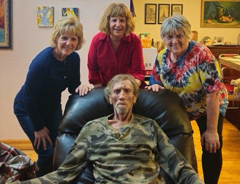 a man in a chair surrounded by 3 women